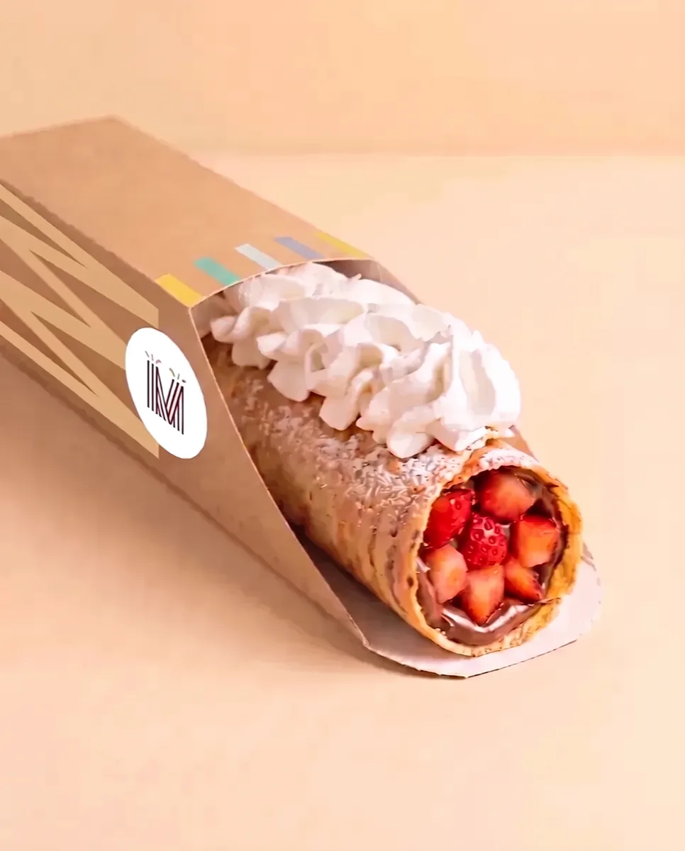 Marquesita de La Marquesita recién armada, con Nutella y fresa, en su funda de cartón